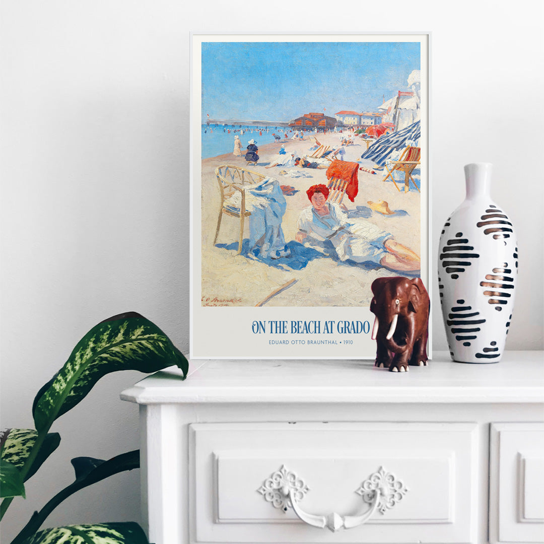 People relaxing on a sunny beach with chairs buildings and colorful umbrellas On the Beach at Grado by Eduard Otto Braunthal, framed and displayed in home decor