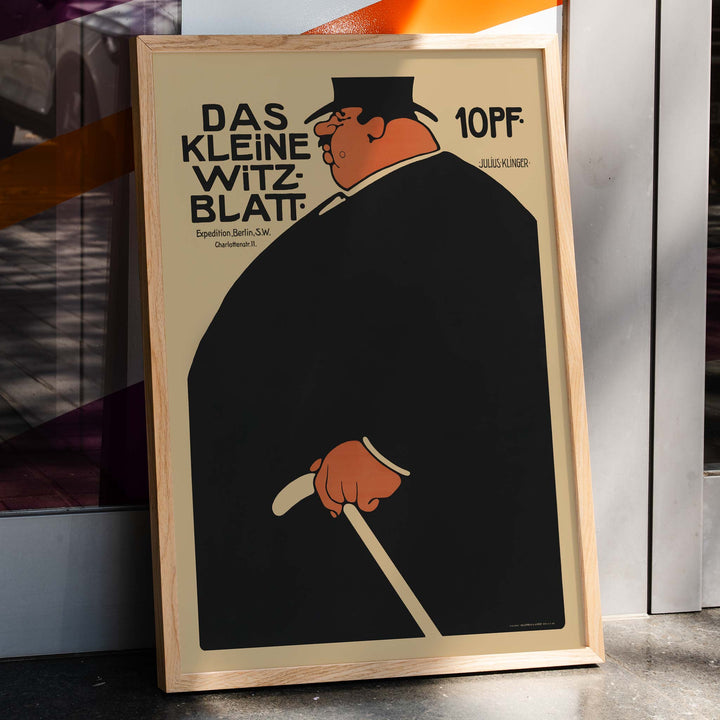 Julius Klinger Das kleine Witzblatt poster with bold black silhouette orange face and hand on beige minimalist background, framed and displayed in home decor