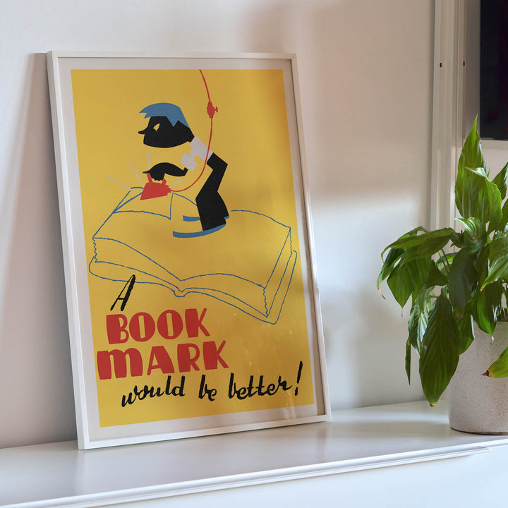 Arlington Gregg A Book Mark Would Be Better poster with stylized open book yellow background and bold red lettering, framed and displayed in modern living room decor