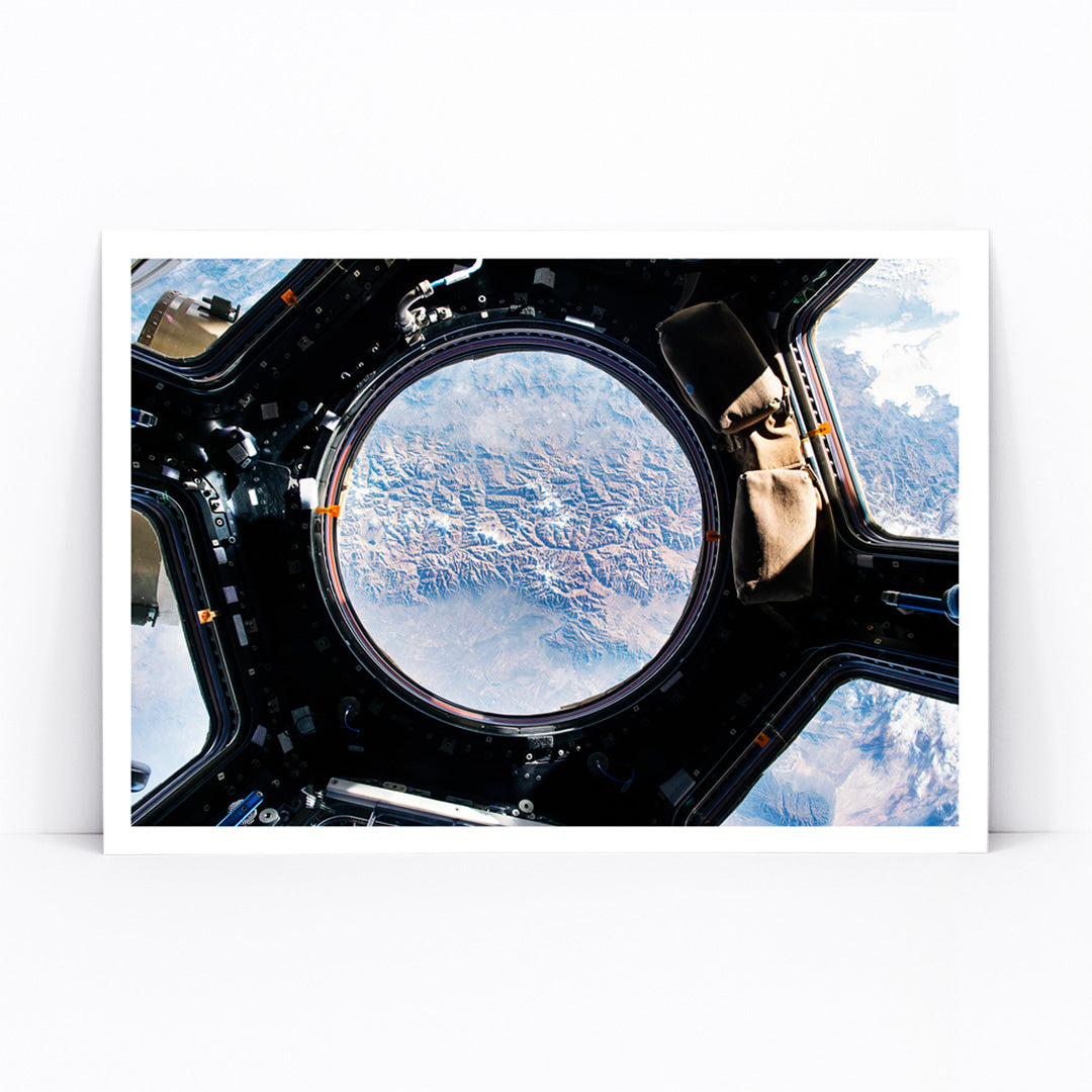 Earth view from International Space Station cupola by NASA with planet visible below poster artwork, framed and displayed in modern living room decor