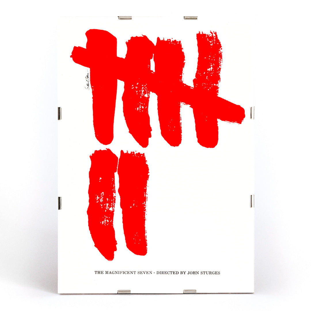 Minimalist movie poster for The Magnificent Seven by Saul Bass with bold red brushstroke tally marks on white background, framed and displayed in modern living room decor