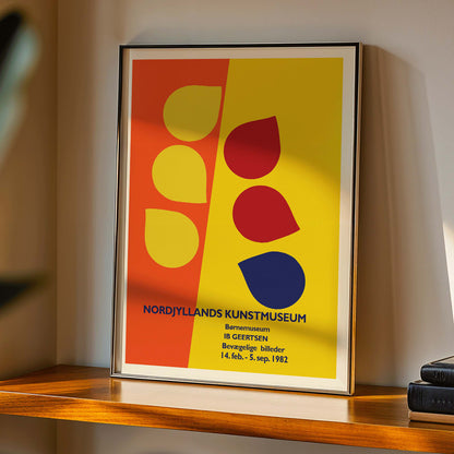 Exhibition poster by Ib Geertsen with colorful geometric shapes in yellow red and blue on an orange and yellow background, framed and displayed in home decor