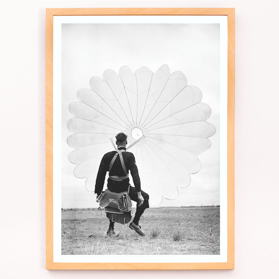 Air force parachuter landing and standing with deployed parachute by Ray Olsen poster, framed and displayed in modern living room decor