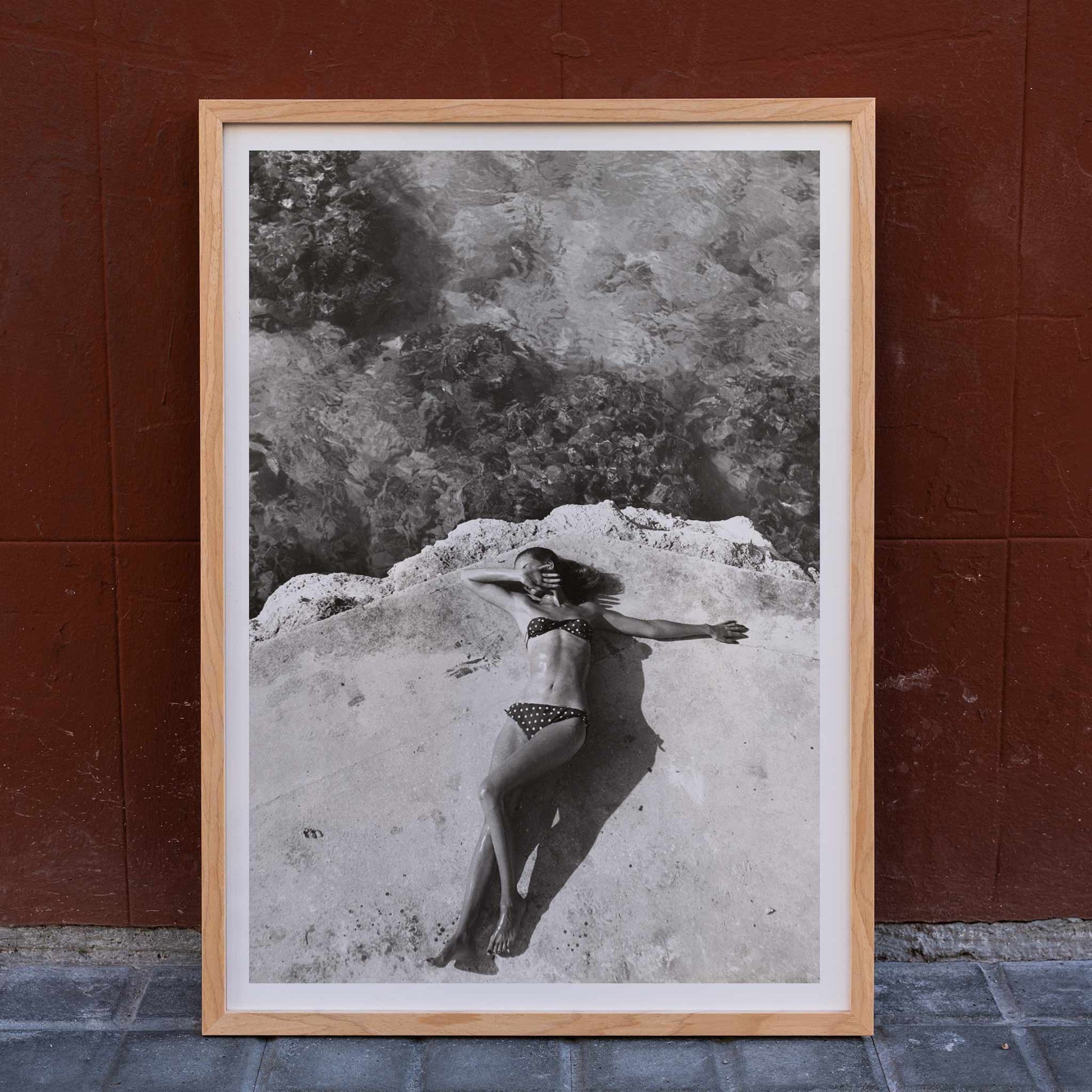 Woman in bikini lying on platform near water in Montego Bay Jamaica artwork by Nickerson Paine poster, framed and displayed in home decor