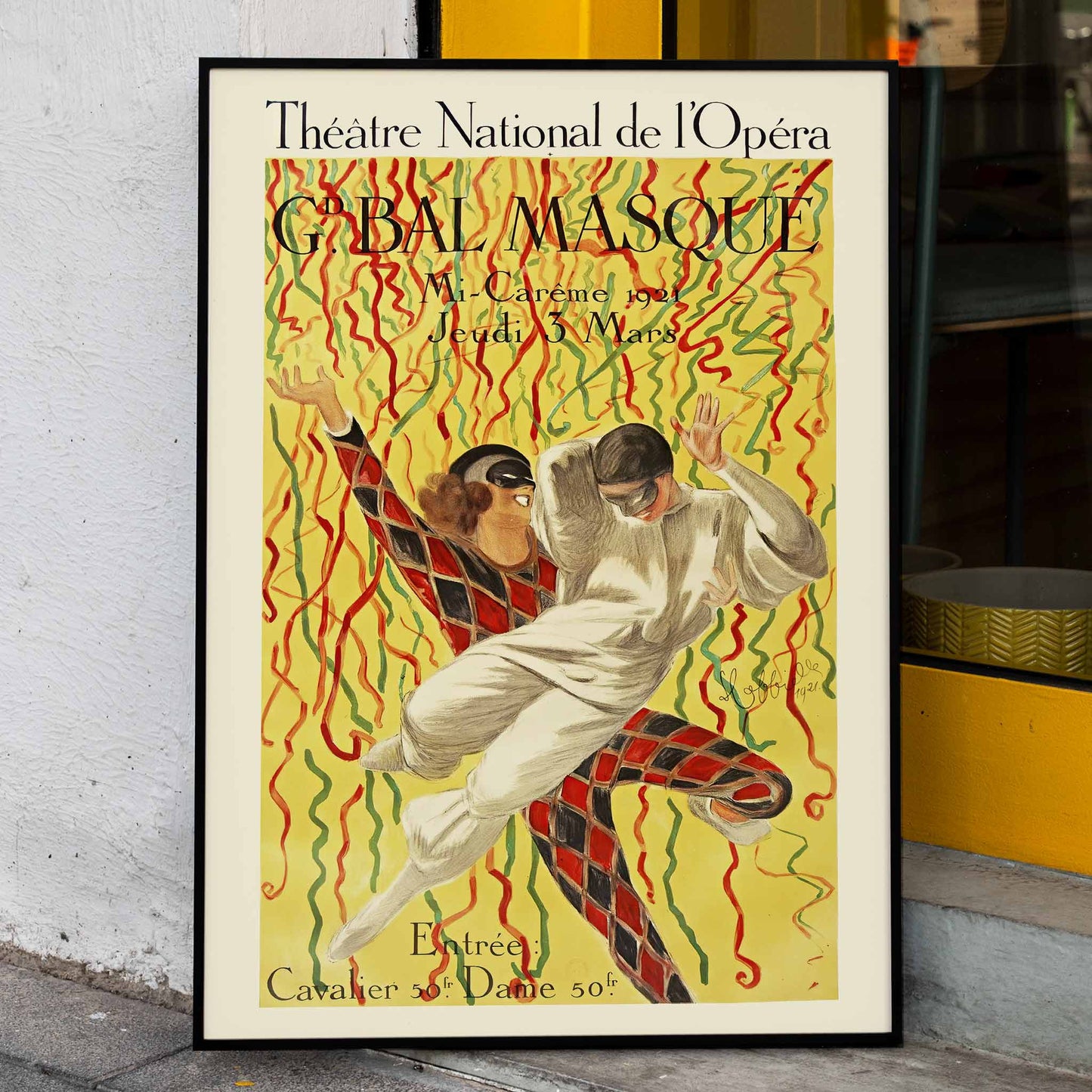 Colorful masquerade ball poster by Leonetto Cappiello featuring two masked dancers with vibrant streamers at the Grand Bal Theatre National De L Opera, framed and displayed in home decor